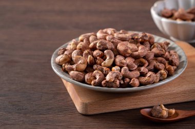 Ahşap tepside kabuklu kaju fıstığı ve masa arkası sağlıklı çiğ gıda konsepti..