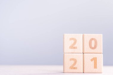 2021 Yeni Yıl Soyut Tasarım Konsepti - Ahşap masa üzerinde izole edilmiş tahta blok küpleri ve açık mavi arka plan.