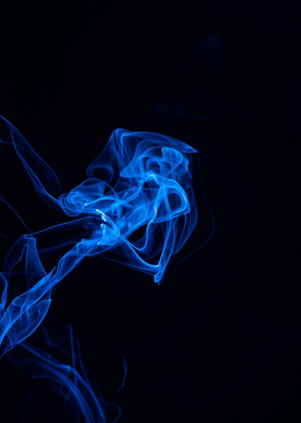 Conceptual image of blue color smoke isolated on dark black background, Halloween concept design element.