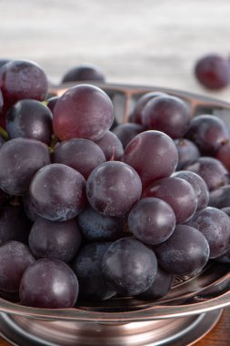 Ahşap masa üzerinde bir tabakta lezzetli üzüm meyveleri..