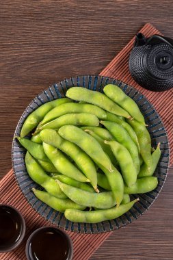 Tahta tepside taze pişmiş edamame tabağı ve fotokopi alanı olan masa arkası, sağlıklı protein besin konsepti..