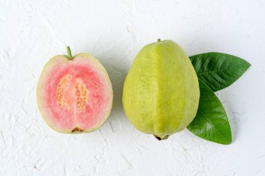 Üst manzara, beyaz masa arkasında izole edilmiş taze yeşil yapraklı leziz kırmızı guava yatağı, fotokopi alanı olan stüdyo masası resmi..