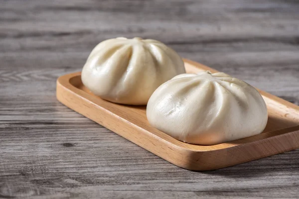 Close up of fresh delicious baozi, Chinese steamed meat bun is ready to eat on serving plate and steamer, close up, copy space product design concept.