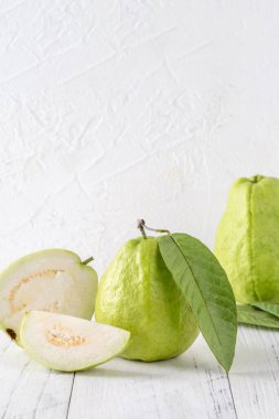 Taze yapraklı nefis guava seti, parlak beyaz ahşap masa arka planında izole edilmiş, yakın plan..