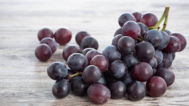 Lezzetli bir demet üzüm meyvesi, ahşap masa arkasında bir tabakta, kapat..