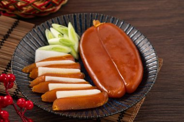 Delicious fresh mullet roe with white radish slices and garlic sprout for Chinese lunar new year gift basket box, holiday celebration.