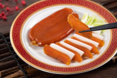 Delicious fresh mullet roe with white radish slices and garlic sprout for Chinese lunar new year gift basket box, holiday celebration.