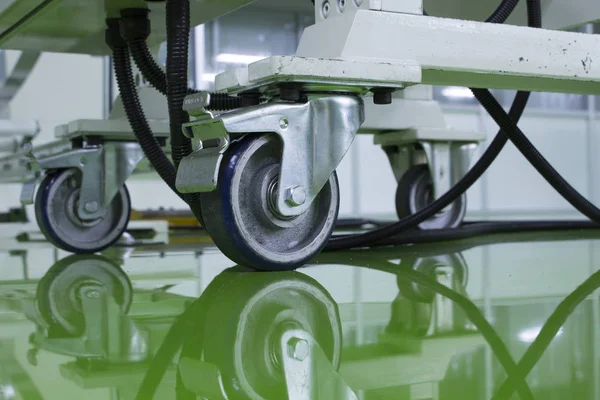 A cable under Table legs on wheels at green epoxy floor. — 스톡 사진