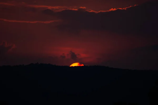 Pôr do sol sobre colinas e céu vermelho sangue da floresta. (silhueta) — Fotografia de Stock