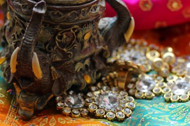 Wooden casket box with oriental patterns elephants full of gold jewelry on Raspberry fabric background