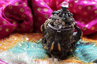 Wooden casket box with oriental patterns elephants full of gold jewelry on Raspberry fabric background