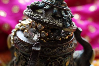 Wooden casket box with oriental patterns elephants full of gold jewelry on Raspberry fabric background