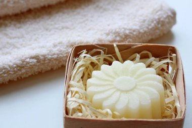 Bir bej havlu ve hafif bir arka plan üzerinde bir çiçek şeklinde bir sabun. Yan görünüm.