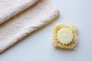 Bir bej havlu ve hafif bir arka plan üzerinde bir çiçek şeklinde bir sabun. Üstte görüntü.
