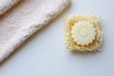 Bir bej havlu ve hafif bir arka plan üzerinde bir çiçek şeklinde bir sabun. Üstte görüntü.