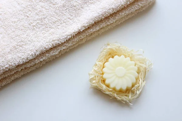 A beige towel and a soap in the form of a flower on a light background. Top view. Royalty Free Stock Photos