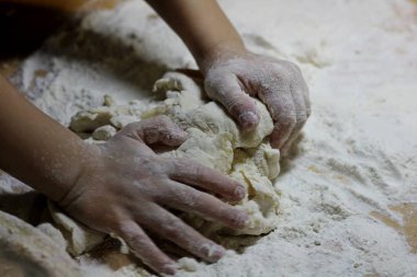 Çocukların elleri ve hamuru. Küçük çocuk hamur yoğuruyor. Sağlıklı el yapımı gıda konsepti. fırın ürünleri, pizza, un. yemek atölyesi. bebeğin elleri ahşap bir masaüzerinde bir hamur dışarı rulo.