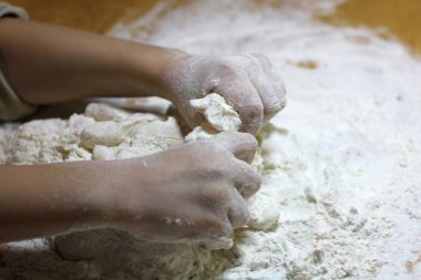 Çocukların elleri ve hamuru. Küçük çocuk hamur yoğuruyor. Sağlıklı el yapımı gıda konsepti. fırın ürünleri, pizza, un. yemek atölyesi. bebeğin elleri ahşap bir masaüzerinde bir hamur dışarı rulo.