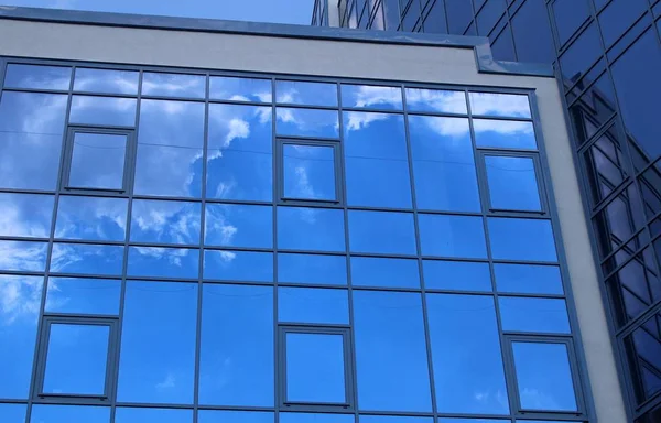Clouds reflected in the many mirrored facets of a modern office building — Stock Photo, Image