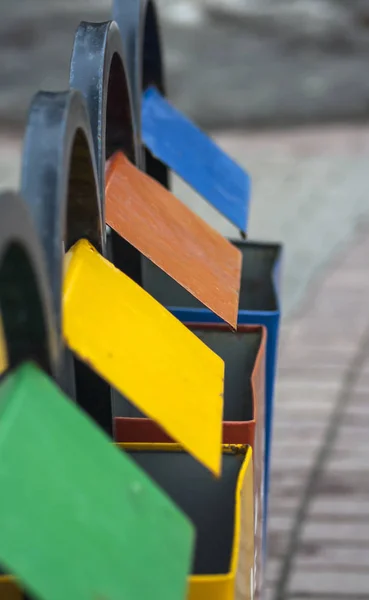 four multi-colored waste bins for separate waste collection stand in a row on the street, a perspective view close-up