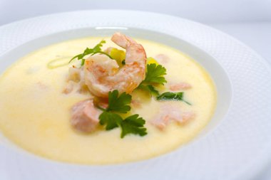 restoranda beyaz bir arka plan üzerinde beyaz bir tabakta gurmeler için pişirilen maydanoz ve limon ile karides krema çorbası büyük kral karides