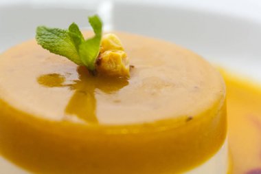 beyaz bir arka plan üzerinde lüks bir restoranda nane ve deniz-buckthorn çilek bir sprig ile parlak turuncu cheesecake