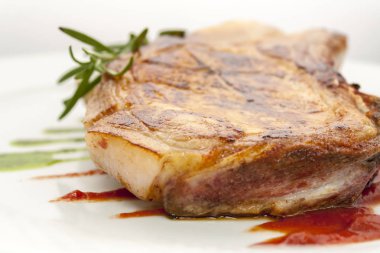 beyaz bir tabak yakın çekim üzerinde biberiye ve domates sosu ile kızarmış domuz pirzolası sulu parça