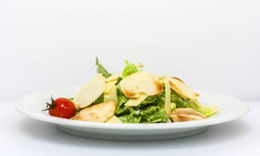 Beyaz arka plan genel görünümünde kruton, peynir, marul ve salamura domates ile Sezar salatası