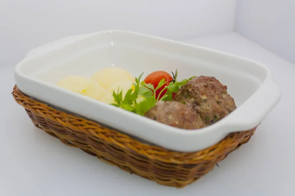 beef meat balls with mashed potatoes and pickled tomatoes in a wicker basket