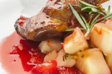 beyaz bir arka plan yakın çekim üzerinde kırmızı elma sosu confiture patates ve biberiye ile kızarmış ördek bacak