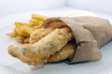 beyaz bir tabak izole üzerinde tartar soslu geleneksel İngiliz balık ve cips