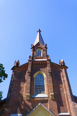 Mavi gökyüzüne karşı küçük kırmızı tuğla Gotik katedral kulesi