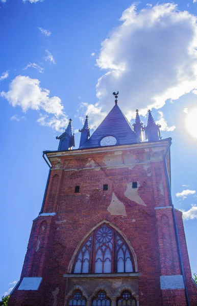 The clock tower of the old castle of red brick against a blue sky