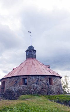 Korela Kalesi. Bir yaz gününde bulutlu gökyüzüne karşı bir hava vane ile müstahkem gözetleme kulesi