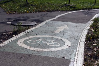 Virajdaki kentsel bir ortamda asfalt üzerinde trafik işareti olan bir bisikleti işaret eden yol tabelası