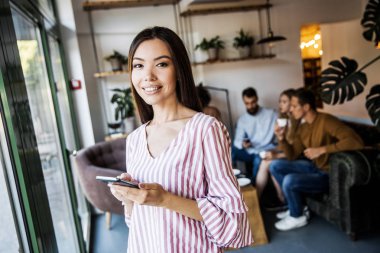kadın iş adamları bulanık arka plan bir sürü önünde bir metin mesajı göndermek için akıllı telefon cihazında bir uygulama kullanıyor