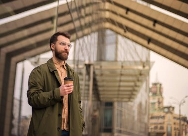 köprüde tek kullanımlık kahve fincanı ile ayakta yakışıklı sakallı adam