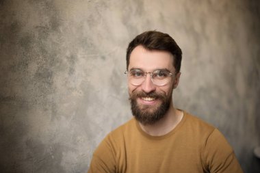 kafelerde kameraya bakarak gözlük gülümseyen yakışıklı sakallı adam