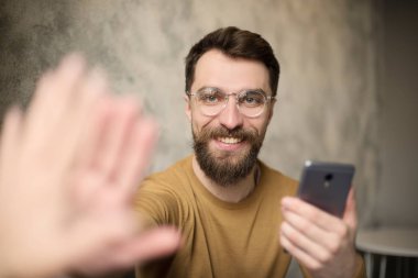 akıllı telefon ile yakışıklı sakallı adam arkadaşına yüksek beş veren