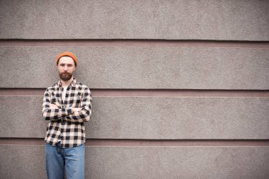 sokakta gri duvar yakınında çapraz kolları ile ayakta yakışıklı sakallı adam