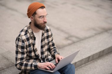 merdivenlerde dizüstü çalışan yakışıklı sakallı adam