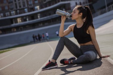 genç güzel koyu saçlı atletik kız spor dışarı asılı, ısınma ve onun sağlığı için spor egzersizleri ve şehir sokak bisiklet pistinde bir koşu bandı üzerinde güçlü bir sağlıklı vücut performans