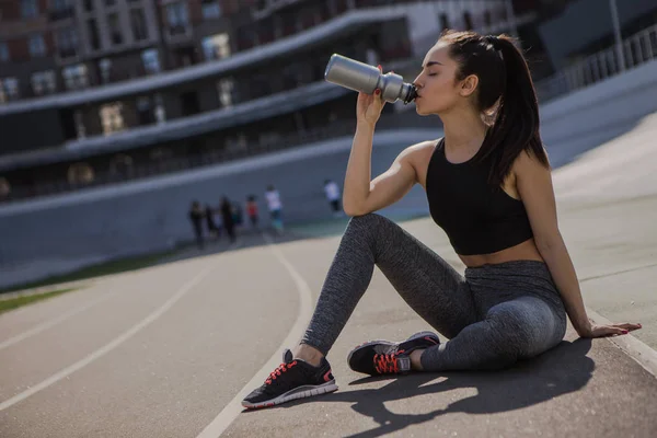 young beautiful dark-haired athletic girl is hanging out in sports, warming up and performing sports exercises for her health and a strong healthy body on a treadmill on the city street cycle track