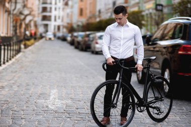 şehirde bisikletle yürüyen gömlek yakışıklı adam