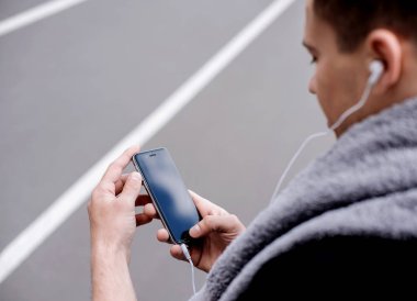 stadyumda akıllı telefon ile müzik dinlehavlu ile yakışıklı sporcu 