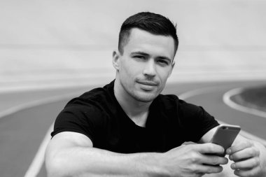 yakışıklı sporcu stadyumda oturan ve akıllı telefon kullanarak