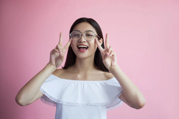 Atraente Sorrindo Menina Asiática Óculos Mostrando Sinais Paz Fundo Rosa — Fotografia de Stock