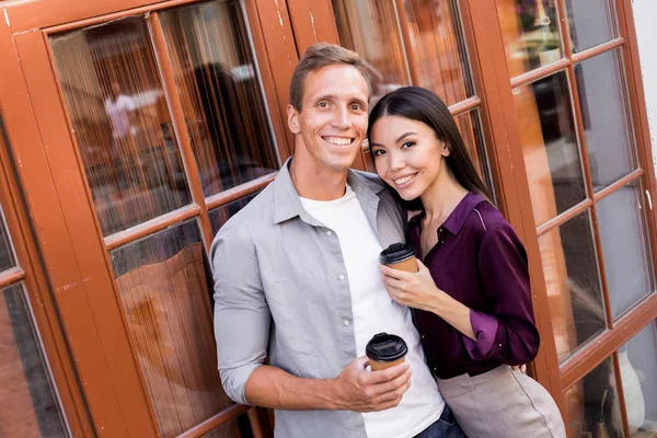 Vrolijke Jonge Paar Met Wegwerp Koffie Kopjes Kijken Naar Camera — Stockfoto