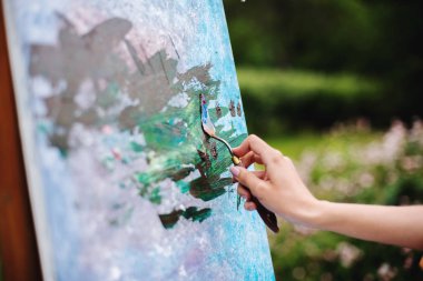 Sanat, yaratıcılık ve insan kavramı. Bahçede stüdyo açık kağıt tuval üzerinde palet ve fırça boyama natürmort ile sanatçıyakın. Tarla çiçekleri resmi