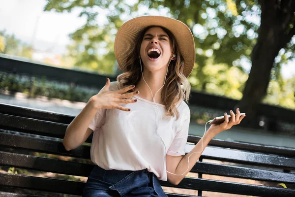 Energy woman singing music and dancing on the city park having fun and enjoing summer